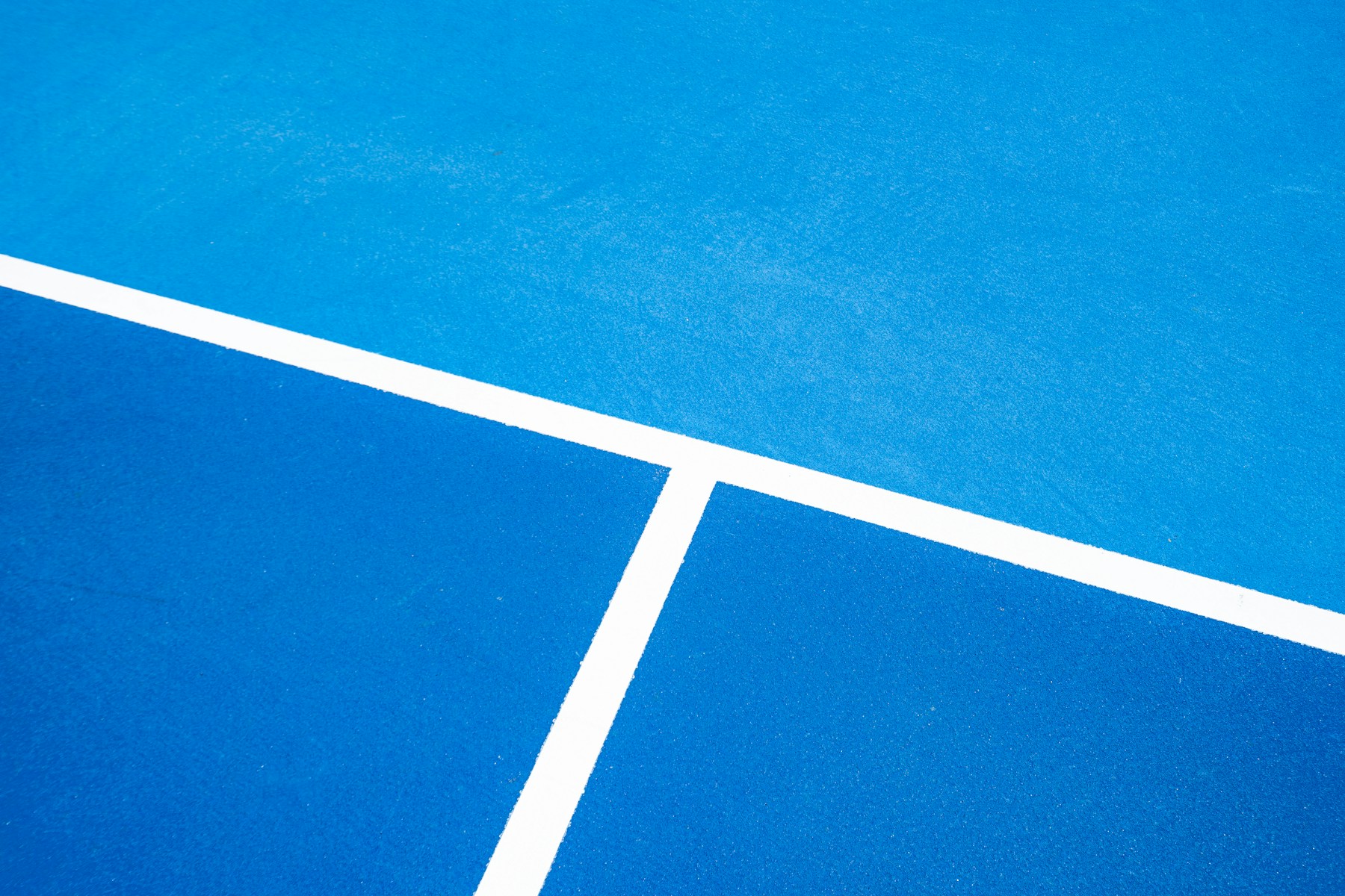 Close view of blue pickleball court surfaces and painted court markings